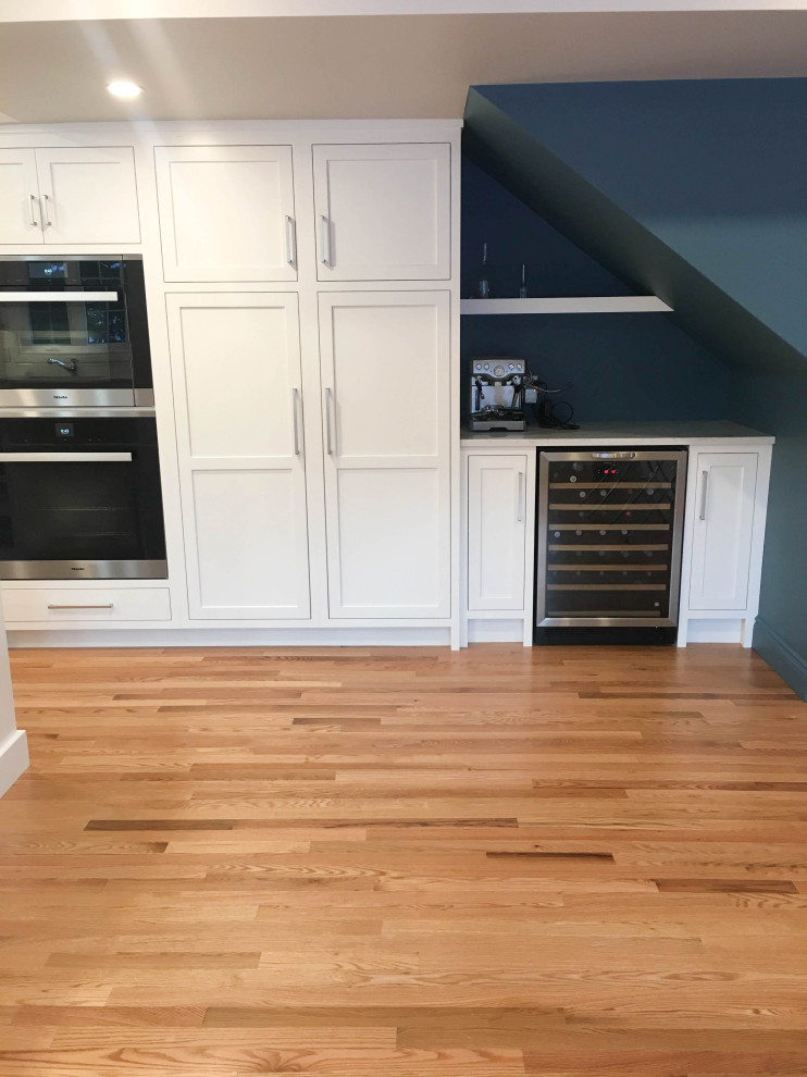 Inspiration for a large transitional u-shaped light wood floor and beige floor eat-in kitchen remodel with a double-bowl sink, shaker cabinets, white cabinets, quartzite countertops, white backsplash, subway tile backsplash, stainless steel appliances, an island and white countertops