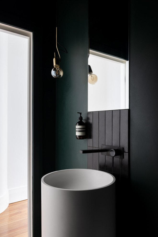 Inspiration for a mid-sized contemporary powder room in Melbourne with a wall-mount toilet, black tile and a freestanding vanity.