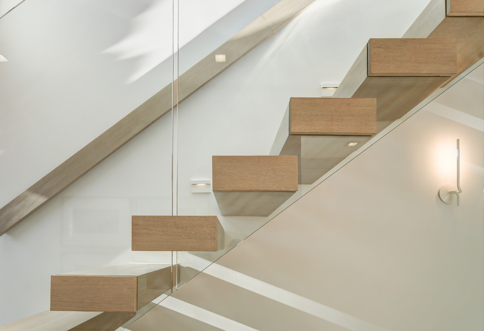This is an example of a modern wood floating staircase in New York with open risers and glass railing.
