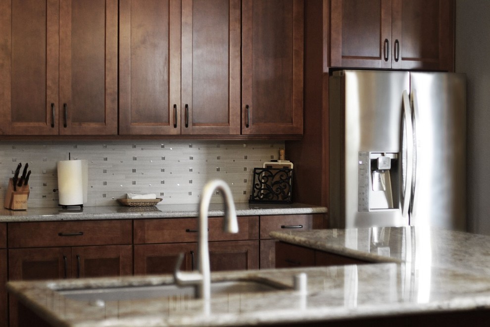 Inspiration for a transitional ceramic tile and beige floor kitchen remodel with an undermount sink, shaker cabinets, granite countertops, white backsplash, glass tile backsplash, stainless steel appliances, an island, white countertops and medium tone wood cabinets