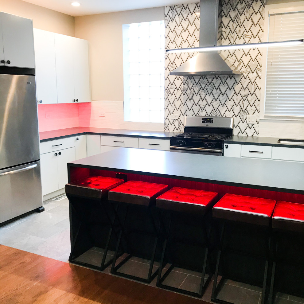 Photo of a mid-sized modern l-shaped eat-in kitchen in Chicago with an undermount sink, flat-panel cabinets, white cabinets, quartz benchtops, white splashback, porcelain splashback, stainless steel appliances, ceramic floors, with island, grey floor and black benchtop.