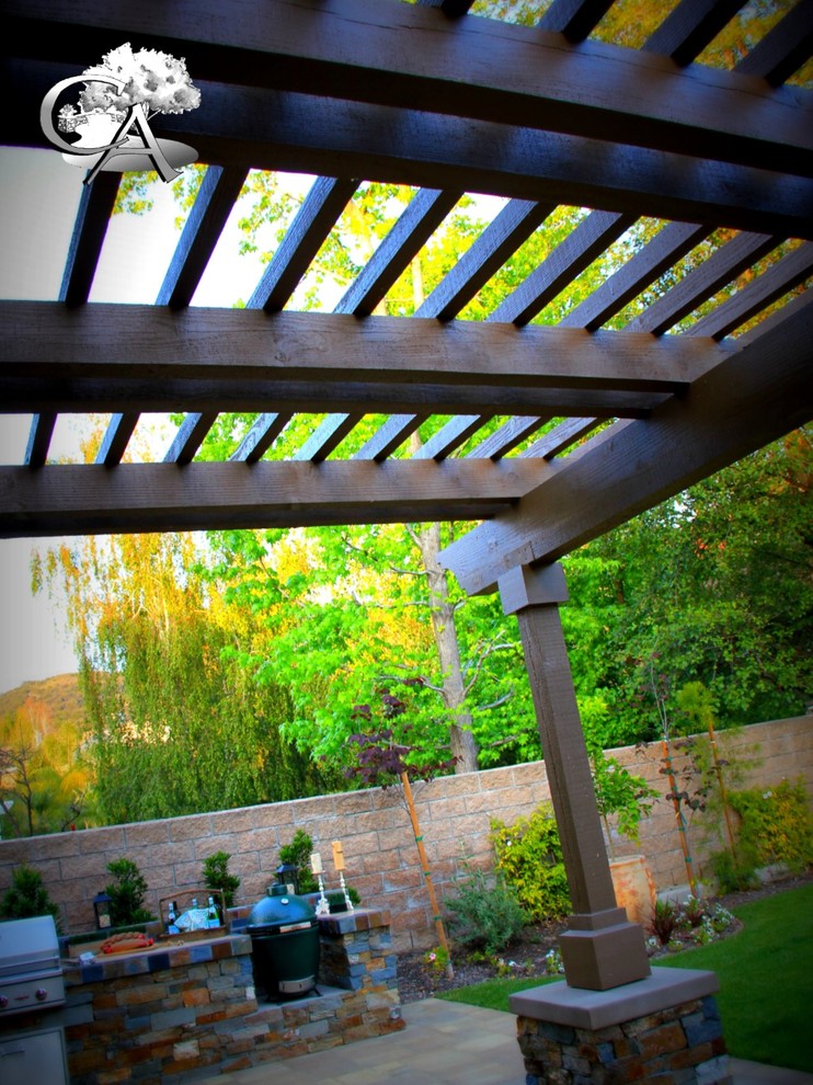 Photo of a mid-sized transitional backyard patio in Orange County with an outdoor kitchen, concrete pavers and a pergola.