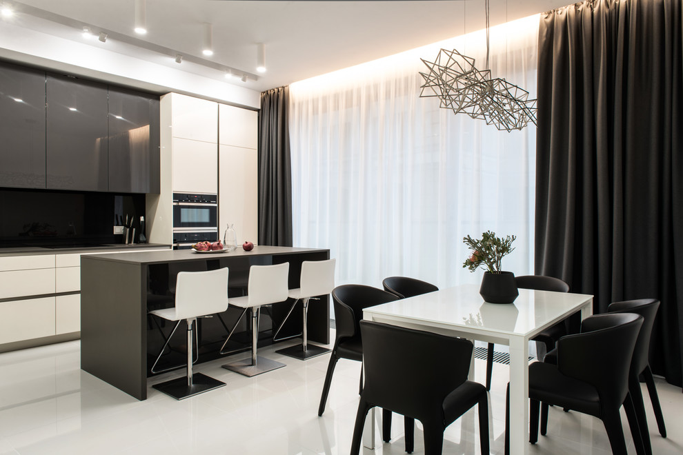 This is an example of a contemporary single-wall kitchen in Moscow with flat-panel cabinets, white cabinets, black splashback, black appliances, with island, white floor and black benchtop.