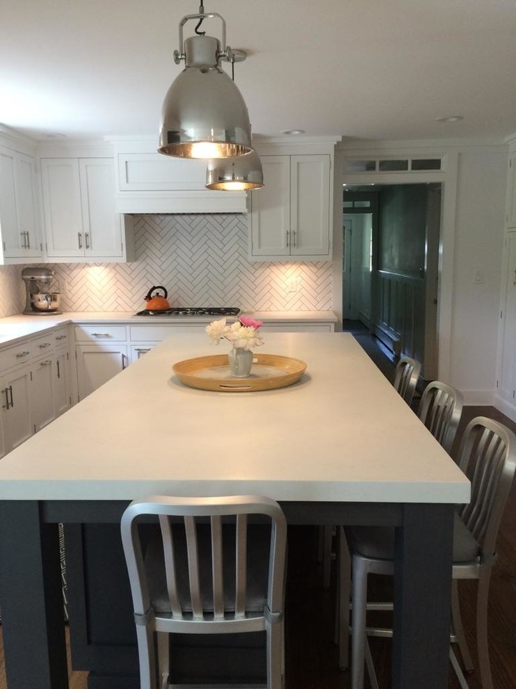 Mid-sized transitional l-shaped dark wood floor and brown floor open concept kitchen photo in New York with an undermount sink, shaker cabinets, white cabinets, limestone countertops, white backsplash, porcelain backsplash, stainless steel appliances and an island