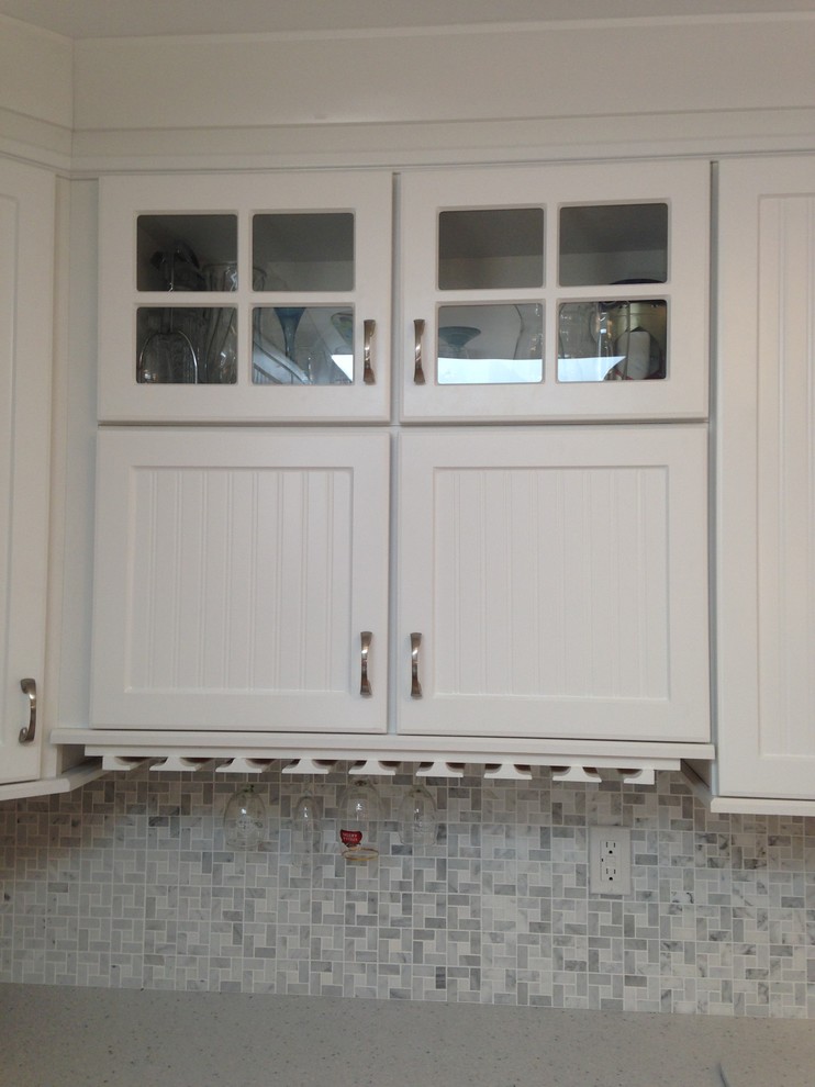 Inspiration for a mid-sized coastal l-shaped eat-in kitchen remodel with an undermount sink, beaded inset cabinets, white cabinets, solid surface countertops, gray backsplash, mosaic tile backsplash, white appliances and a peninsula