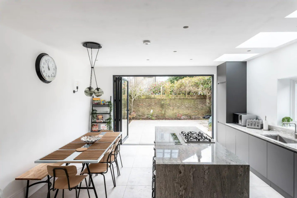 Inspiration for a large modern galley open plan kitchen in Sussex with an integrated sink, flat-panel cabinets, grey cabinets, granite benchtops, multi-coloured splashback, granite splashback, stainless steel appliances, porcelain floors, a peninsula, grey floor, multi-coloured benchtop and recessed.