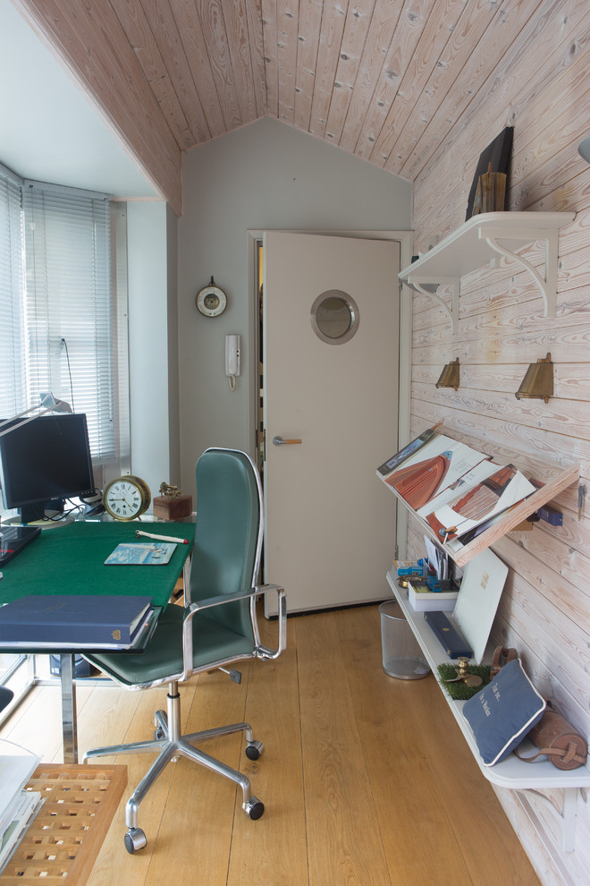 This is an example of a small beach style home office in London with medium hardwood flooring and a freestanding desk.
