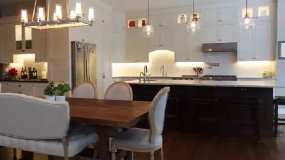 Inspiration for a mid-sized transitional l-shaped medium tone wood floor and brown floor eat-in kitchen remodel with a double-bowl sink, shaker cabinets, white cabinets, quartzite countertops, white backsplash, subway tile backsplash, stainless steel appliances and an island