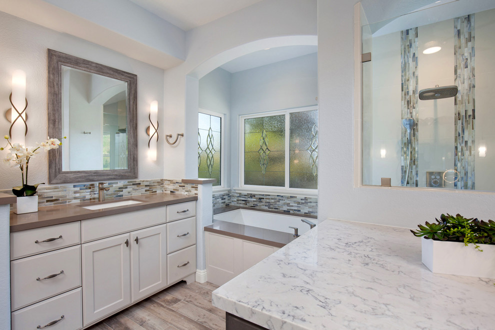 Inspiration for a large transitional master bathroom in San Diego with shaker cabinets, white cabinets, an undermount tub, an alcove shower, porcelain floors, an undermount sink, a one-piece toilet, blue tile, mosaic tile, grey walls, engineered quartz benchtops, grey floor and a hinged shower door.