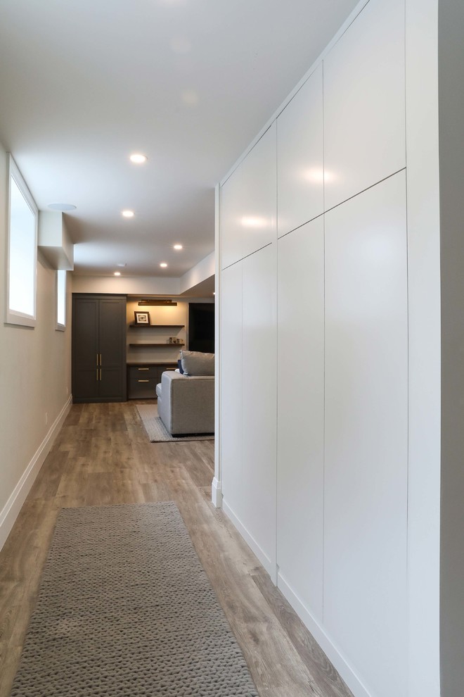 Inspiration for a large transitional look-out vinyl floor and brown floor basement remodel with white walls