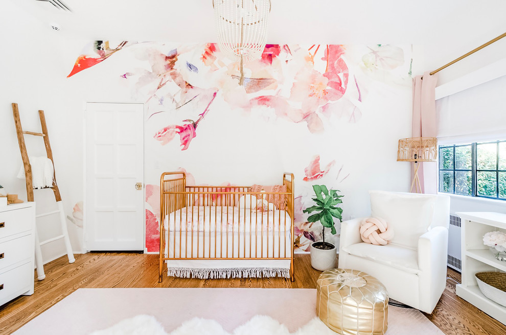 This is an example of a large transitional nursery for girls in New York with white walls, medium hardwood floors and brown floor.