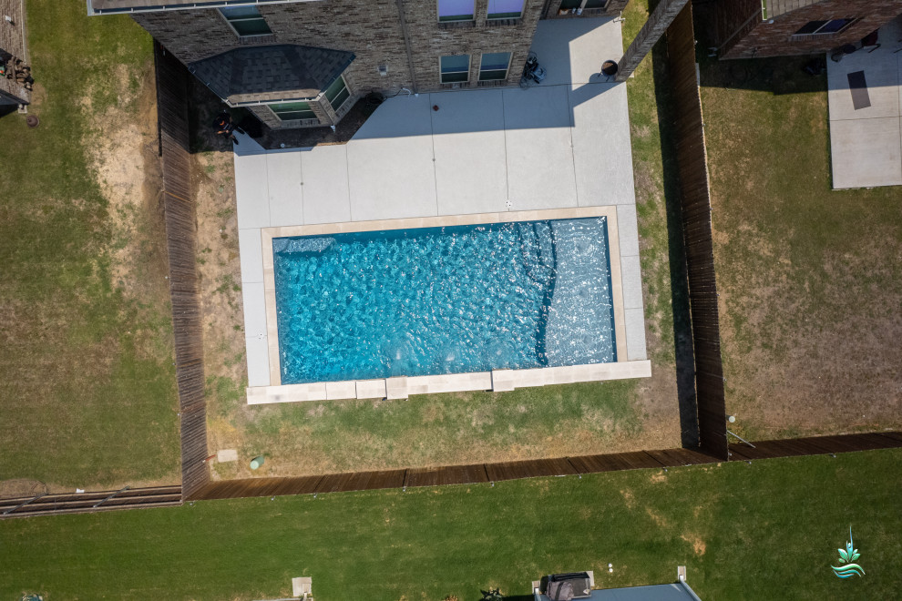 This is an example of a medium sized traditional back rectangular lengths swimming pool in Dallas with with pool landscaping and concrete slabs.