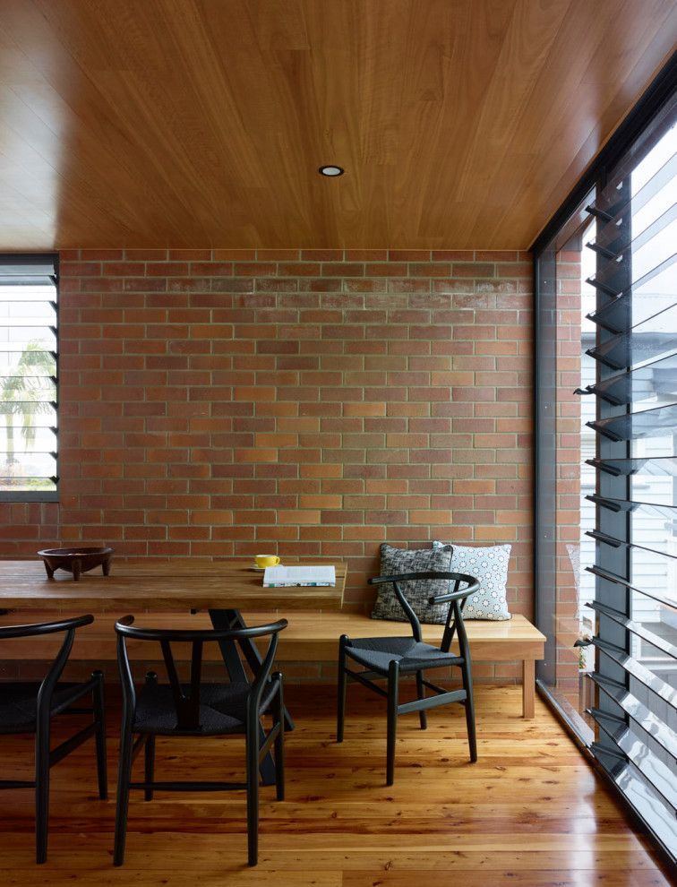 Cette photo montre une salle à manger ouverte sur le salon rétro de taille moyenne avec un mur blanc, parquet clair, un sol marron, un plafond en lambris de bois et un mur en parement de brique.