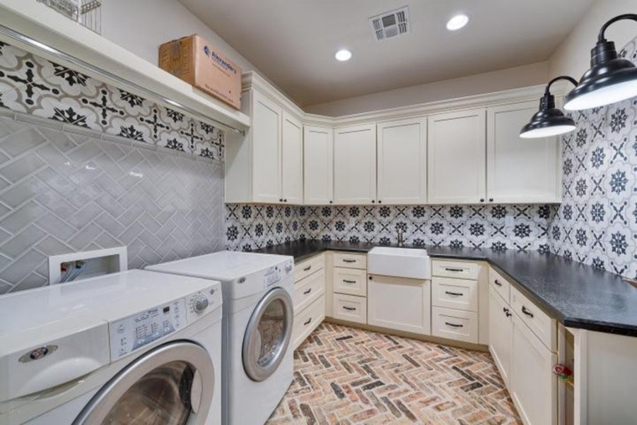 Large contemporary u-shaped laundry room in Phoenix with a farmhouse sink, shaker cabinets, white cabinets, brick floors and a side-by-side washer and dryer.