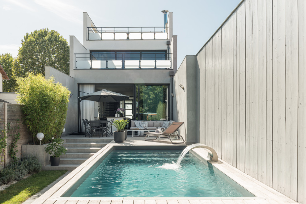 Aménagement d'une piscine hors-sol et arrière moderne de taille moyenne et rectangle avec un point d'eau et des pavés en pierre naturelle.