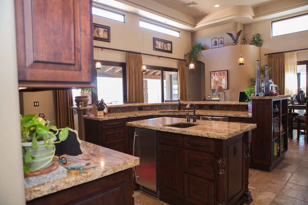 Inspiration for a large transitional u-shaped travertine floor eat-in kitchen remodel in Phoenix with a drop-in sink, raised-panel cabinets, dark wood cabinets, granite countertops, multicolored backsplash, glass tile backsplash, stainless steel appliances and an island