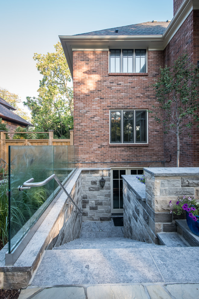 Photo of an expansive transitional two-storey beige exterior in Toronto with stone veneer and a flat roof.