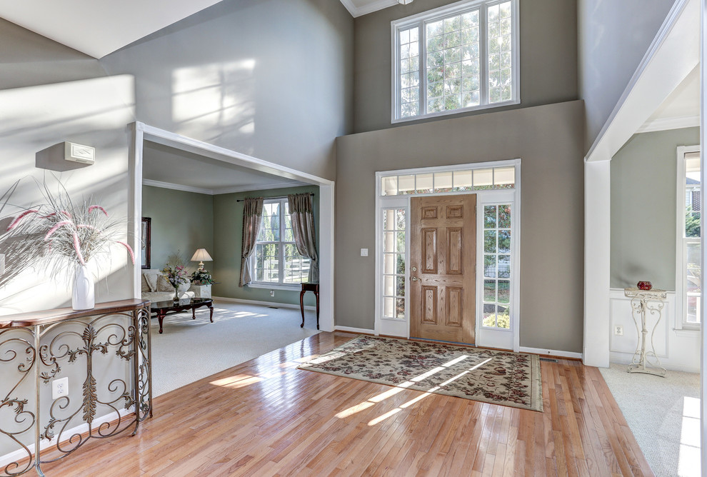 Example of a large transitional medium tone wood floor single front door design in DC Metro with gray walls and a medium wood front door