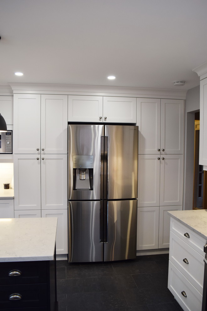 Inspiration for a mid-sized transitional l-shaped ceramic tile enclosed kitchen remodel in Ottawa with an undermount sink, shaker cabinets, white cabinets, quartz countertops, white backsplash, subway tile backsplash, stainless steel appliances and an island