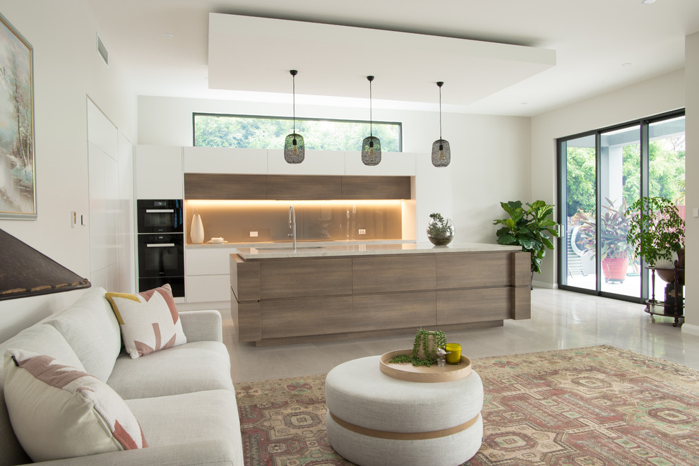 Expansive contemporary galley open plan kitchen in Sydney with an undermount sink, flat-panel cabinets, white cabinets, quartz benchtops, brown splashback, glass sheet splashback, black appliances, ceramic floors, with island, grey floor and white benchtop.