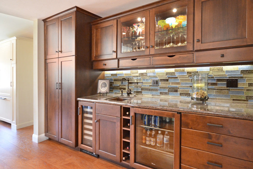 Mid-sized traditional single-wall wet bar in San Francisco with an undermount sink, recessed-panel cabinets, dark wood cabinets, granite benchtops, multi-coloured splashback, glass tile splashback and medium hardwood floors.