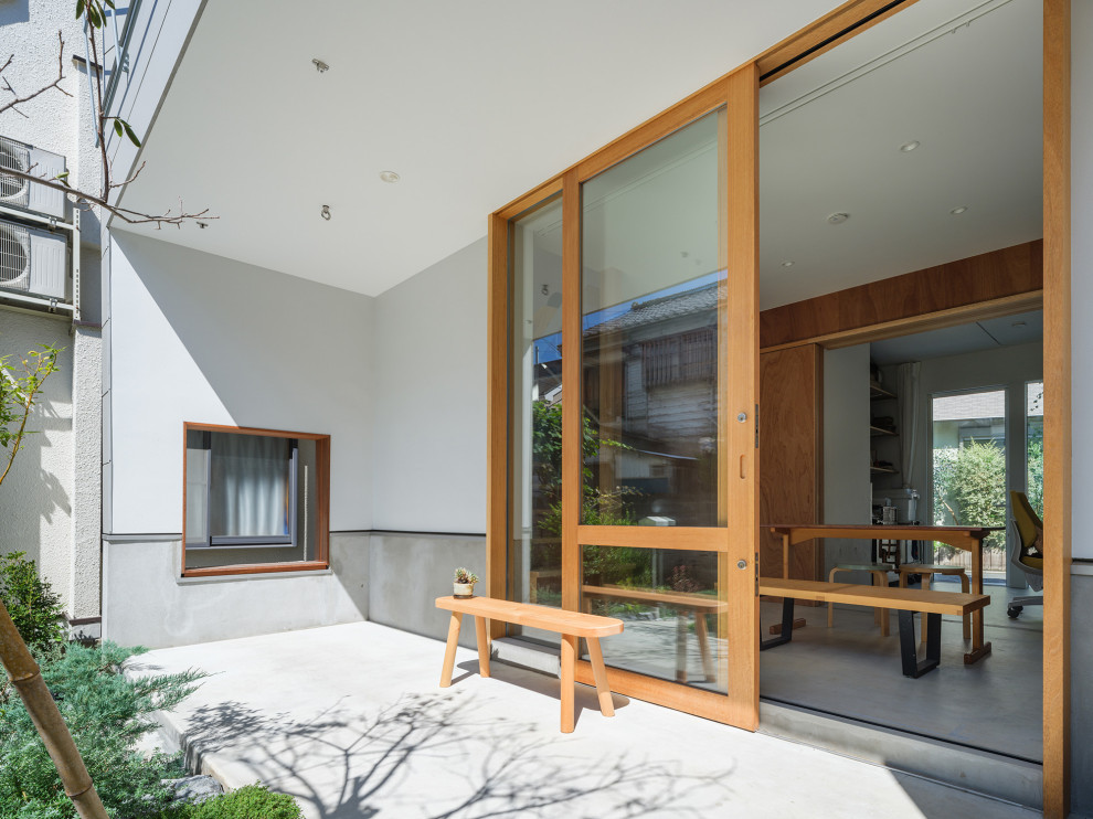 Idee per un patio o portico moderno di medie dimensioni e davanti casa con pavimentazioni in cemento e un tetto a sbalzo