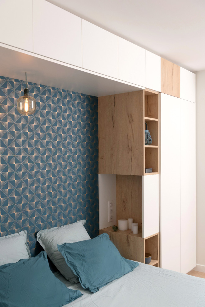 Diseño de dormitorio principal y blanco y madera actual de tamaño medio con paredes azules, suelo de madera clara y madera