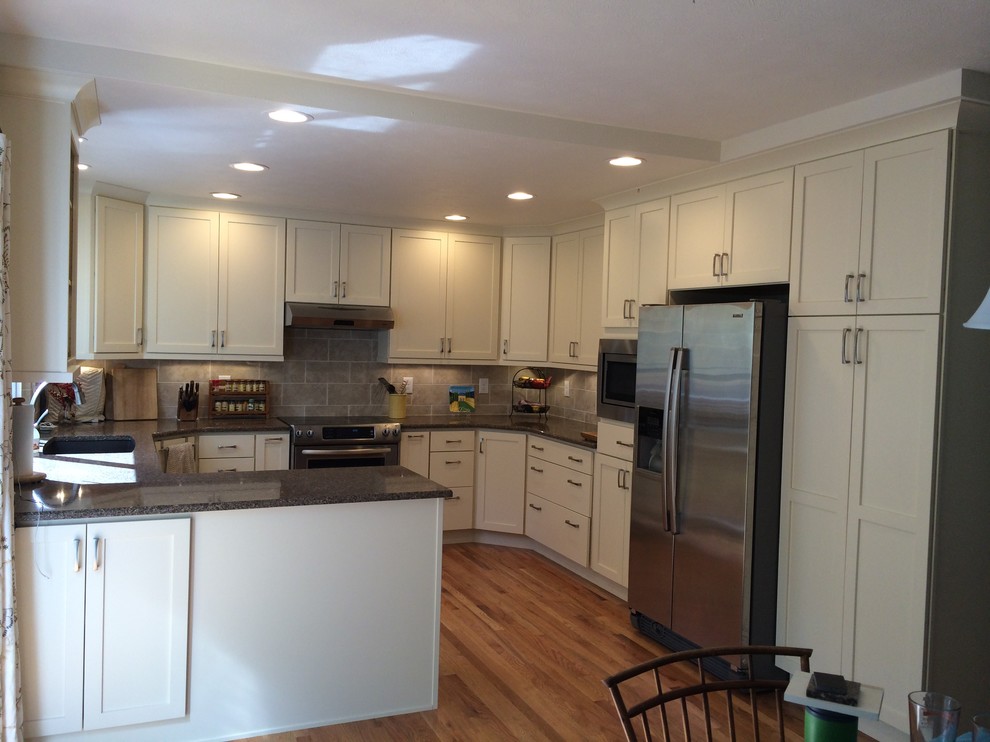 Medium tone wood floor kitchen photo in Denver with recessed-panel cabinets, white cabinets, gray backsplash and stainless steel appliances
