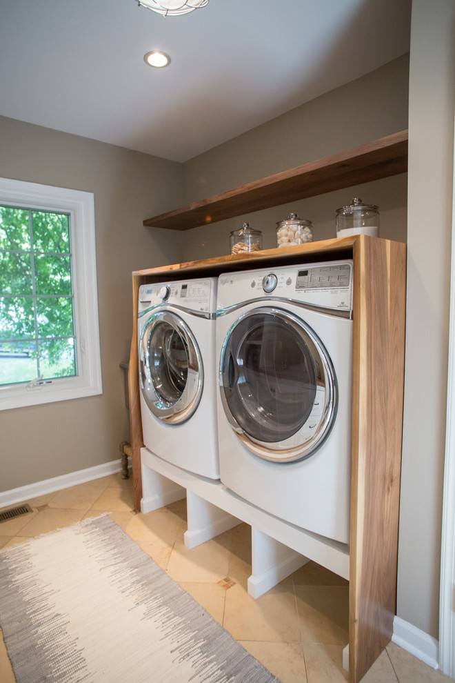 This is an example of a large transitional galley utility room in Philadelphia with shaker cabinets, white cabinets, wood benchtops, beige walls, ceramic floors, a side-by-side washer and dryer and brown benchtop.