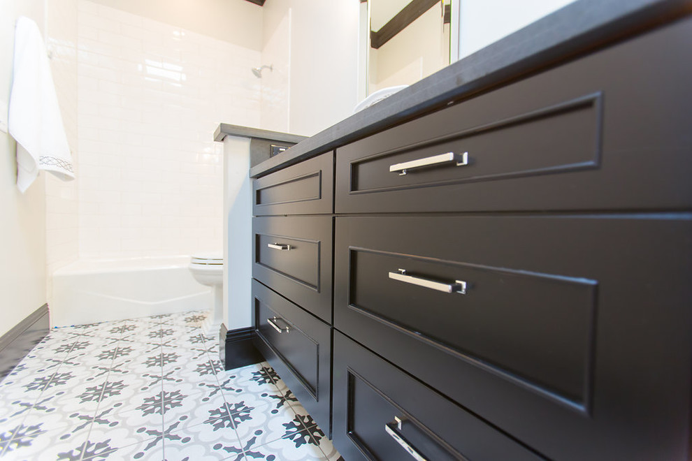 Photo of a large transitional 3/4 bathroom in Phoenix with an alcove tub, a one-piece toilet, white tile, an undermount sink, subway tile, black cabinets, recessed-panel cabinets, a shower/bathtub combo, grey walls, cement tiles, granite benchtops, multi-coloured floor and a shower curtain.