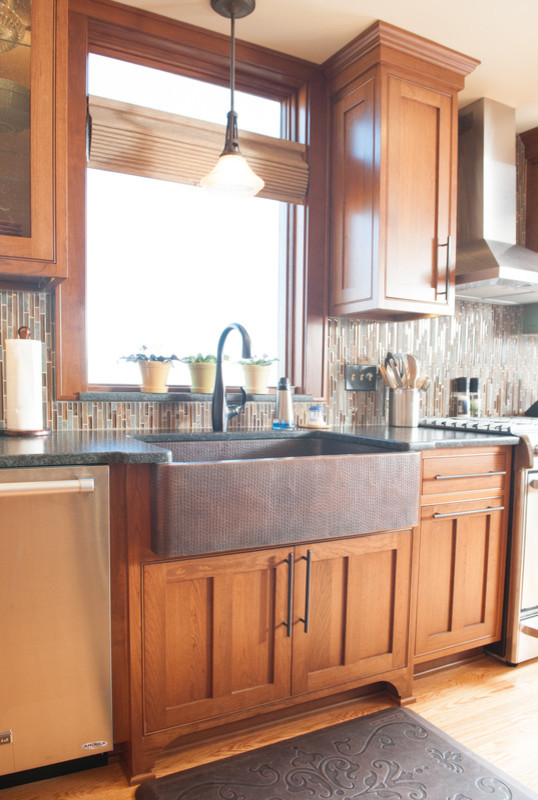 Mid-sized transitional l-shaped medium tone wood floor eat-in kitchen photo in Orange County with a farmhouse sink, shaker cabinets, medium tone wood cabinets, granite countertops, multicolored backsplash, matchstick tile backsplash, stainless steel appliances and an island