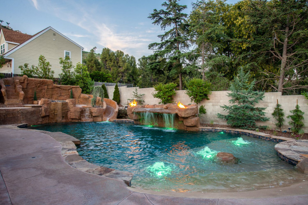 Expansive country backyard custom-shaped natural pool in Orange County with a water feature and concrete slab.
