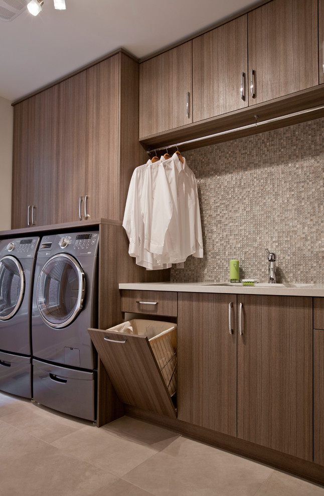 Photo of a mid-sized contemporary single-wall utility room in Toronto with flat-panel cabinets, beige walls, a side-by-side washer and dryer and grey cabinets.