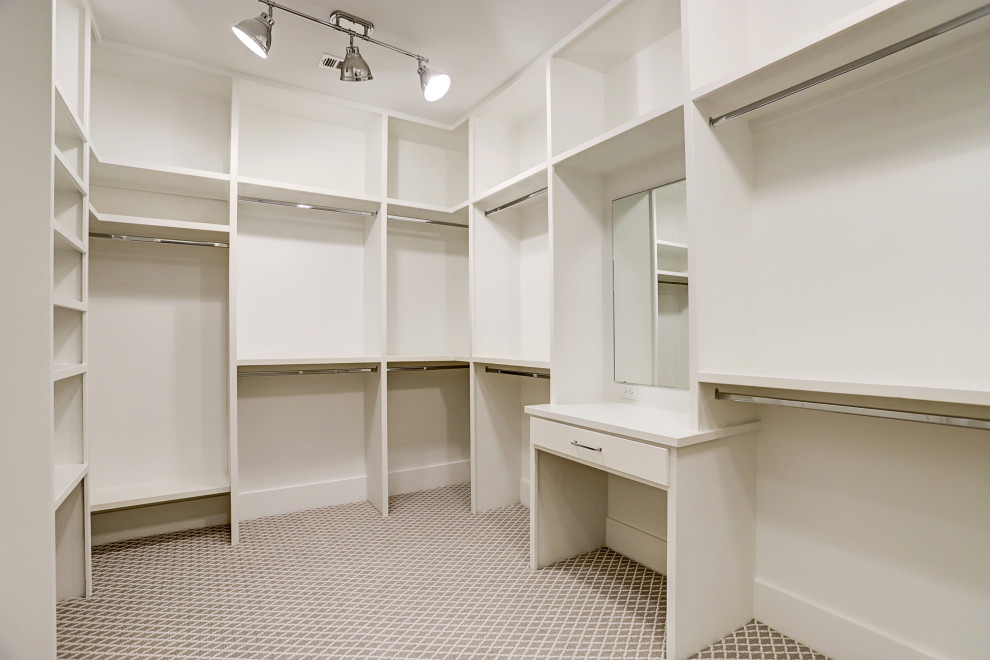 Photo of a large transitional storage and wardrobe in Houston with white cabinets and grey floor.