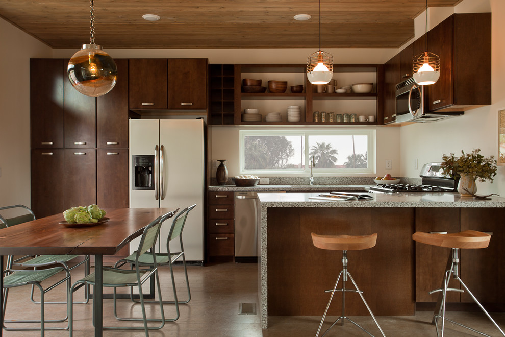 Inspiration for a transitional u-shaped eat-in kitchen in Los Angeles with flat-panel cabinets, dark wood cabinets, white appliances and a peninsula.