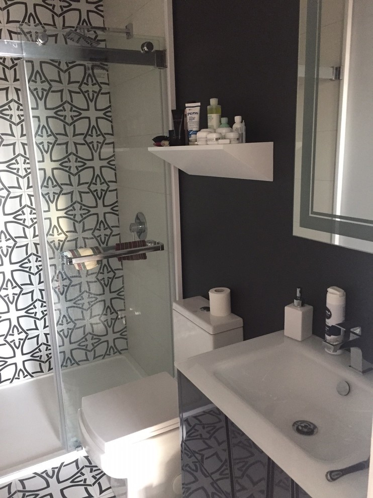 Design ideas for a small 3/4 bathroom in New York with glass-front cabinets, black cabinets, an alcove shower, a one-piece toilet, multi-coloured tile, cement tile, multi-coloured walls, cement tiles, an integrated sink, multi-coloured floor and a sliding shower screen.