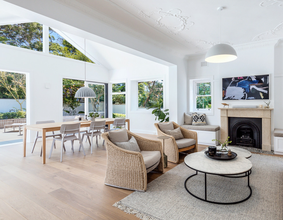 Large beach style open concept living room in Sydney with white walls, medium hardwood floors, a standard fireplace, a stone fireplace surround, a wall-mounted tv and brown floor.