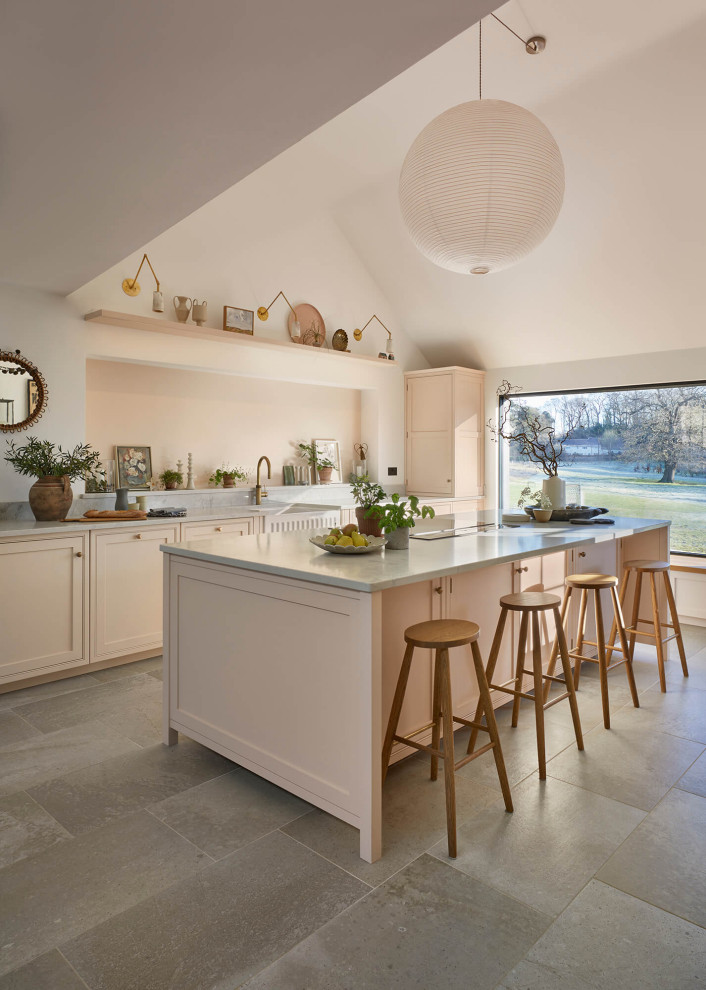 Inspiration for a large rural grey and pink single-wall open plan kitchen in London with a belfast sink, shaker cabinets, pink cabinets, quartz worktops, pink splashback, black appliances, ceramic flooring, an island, multi-coloured floors, grey worktops and a vaulted ceiling.
