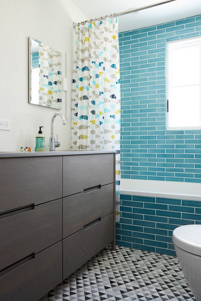 Réalisation d'une salle de bain design de taille moyenne pour enfant avec un placard à porte plane, des portes de placard grises, une baignoire posée, un combiné douche/baignoire, WC suspendus, un carrelage bleu, des carreaux de porcelaine, un mur bleu, un sol en marbre, un lavabo encastré, un plan de toilette en surface solide, un sol gris, un plan de toilette gris, meuble double vasque et meuble-lavabo sur pied.