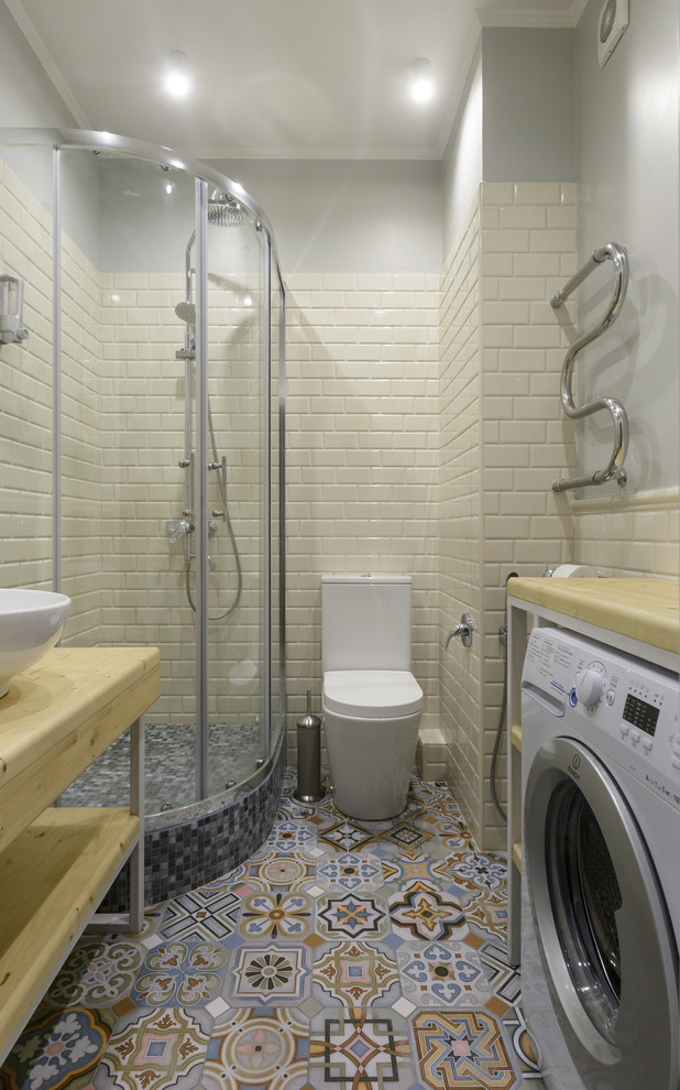 Contemporary 3/4 bathroom in Saint Petersburg with a corner shower, a one-piece toilet, subway tile, porcelain floors, wood benchtops, multi-coloured floor, a sliding shower screen, open cabinets, beige tile, grey walls, a vessel sink and beige benchtops.