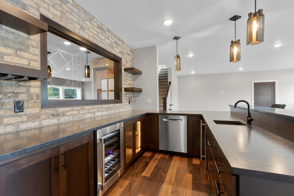 Basement - large transitional walk-out medium tone wood floor, brown floor and brick wall basement idea with a bar, a standard fireplace and a stone fireplace