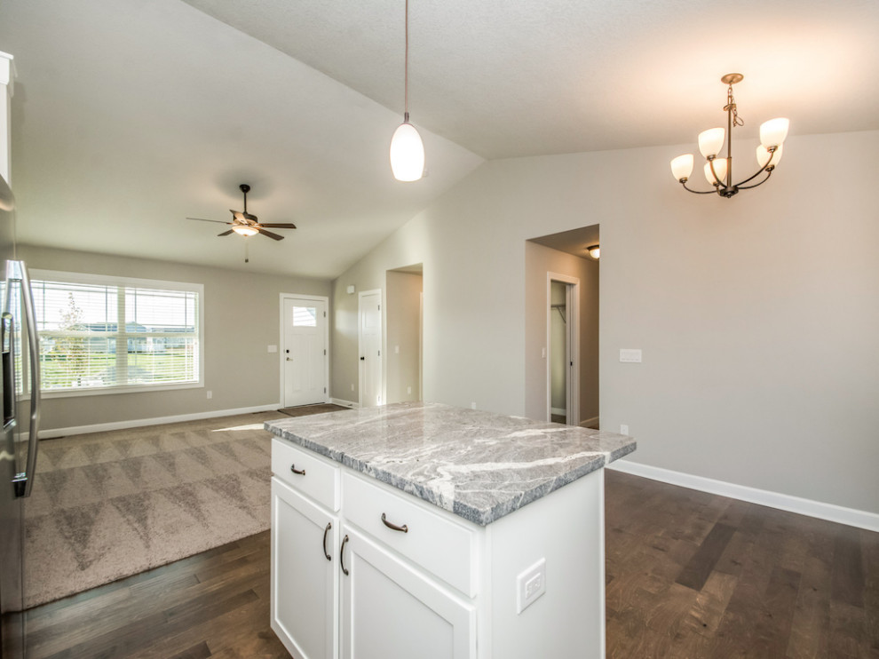 Large transitional medium tone wood floor and brown floor eat-in kitchen photo with an undermount sink, shaker cabinets, white cabinets, granite countertops, white backsplash, subway tile backsplash, stainless steel appliances, an island and multicolored countertops