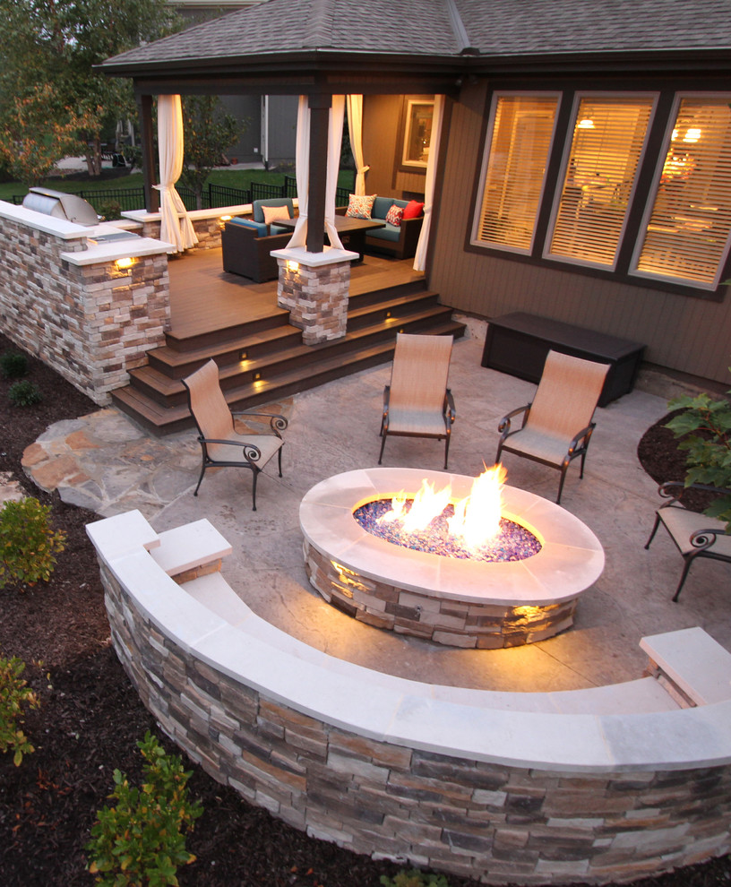 This is an example of a large contemporary backyard patio in Kansas City with a fire feature, stamped concrete and a roof extension.