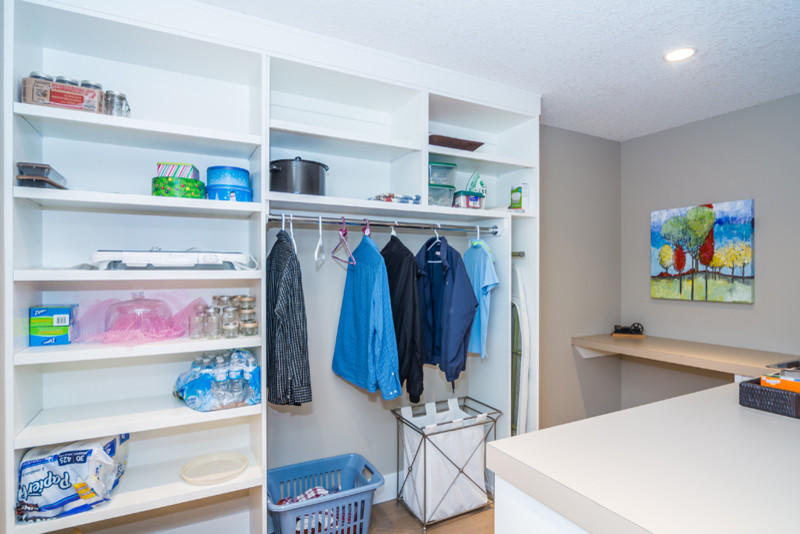 Photo of a large galley utility room in Calgary with an utility sink, shaker cabinets, white cabinets, laminate benchtops, beige walls, cork floors and a side-by-side washer and dryer.