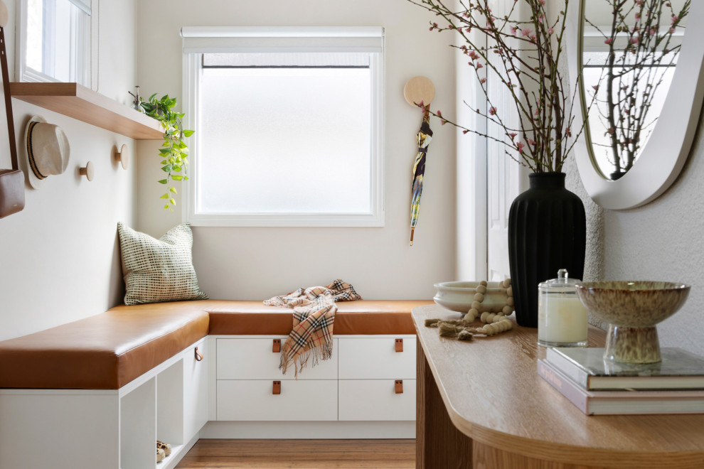 Inspiration for a small contemporary mudroom in Melbourne with white walls, medium hardwood floors, a single front door, brown floor, recessed and panelled walls.