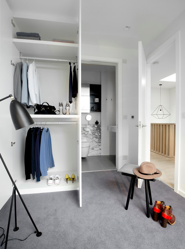 Design ideas for a mid-sized contemporary gender-neutral walk-in wardrobe in London with carpet, open cabinets, white cabinets and grey floor.