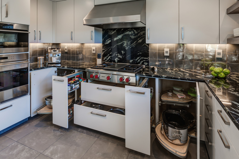 This is an example of a mid-sized contemporary u-shaped eat-in kitchen in San Francisco with an undermount sink, flat-panel cabinets, white cabinets, granite benchtops, metallic splashback, metal splashback, stainless steel appliances, porcelain floors and no island.
