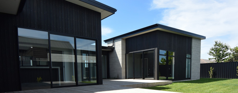 Ispirazione per la facciata di una casa nera moderna con rivestimento in cemento e tetto nero