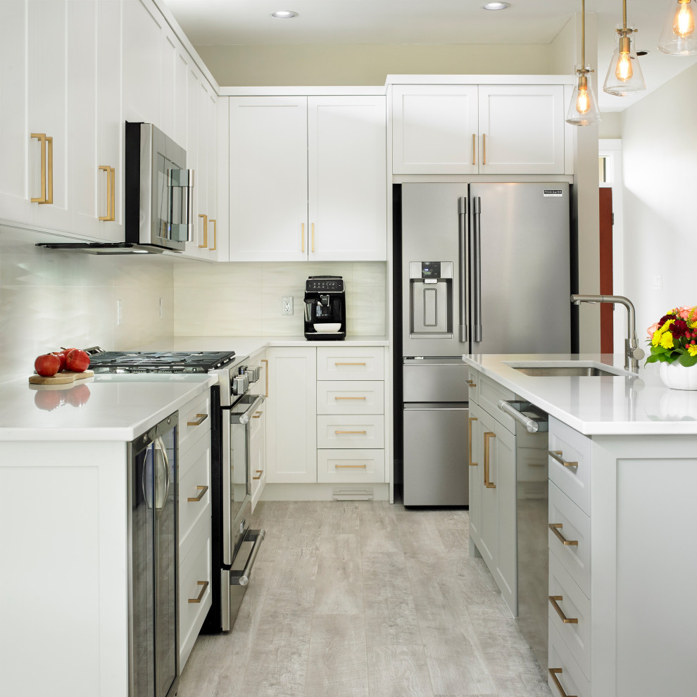 Inspiration for a mid-sized transitional l-shaped beige floor open concept kitchen remodel with an undermount sink, shaker cabinets, white cabinets, quartz countertops, white backsplash, ceramic backsplash, stainless steel appliances and an island