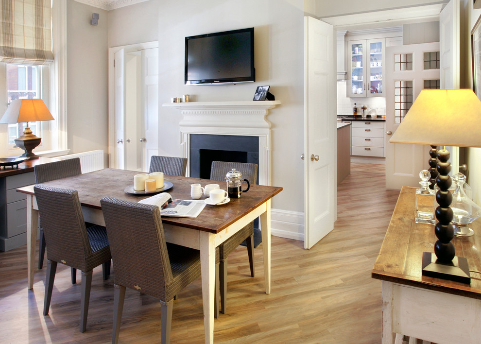 Transitional separate dining room in London with grey walls, light hardwood floors and a standard fireplace.
